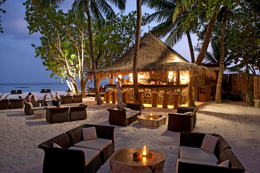 酒吧位于泳池背后的海滩上,在茂密的土著树树冠下,用民族漂木雕刻装饰